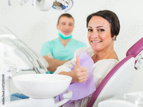 positive patient female thumbs up about work of dantist in medical room photo