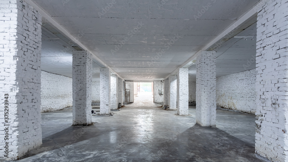 The interior of a huge industrial warehouse made of white bricks with a high ceiling for storing goods. 
