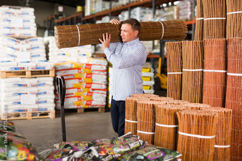 Portrait of man buying braided wooden fence in hypermarket