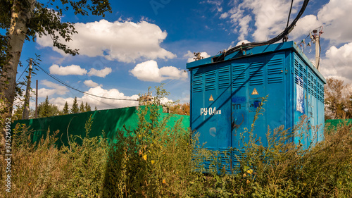 Electric  blue transformer room building with doors and  hazard signs on blue sky background aganst industrial Zone photo