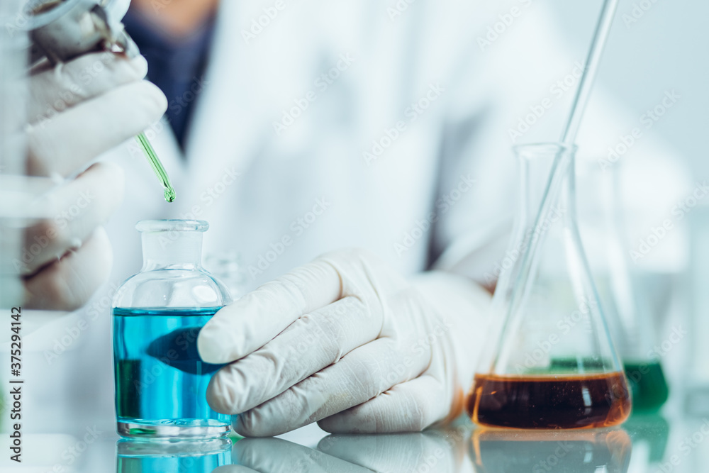 Hand of Biochemical research scientist working with science laboratory test tubes for coronavirus vaccine development in pharmaceutical research labolatory. Hand of Biochemical research scientist working with science laboratory test tubes for coronavirus vaccine development in pharmaceutical research labolatory.