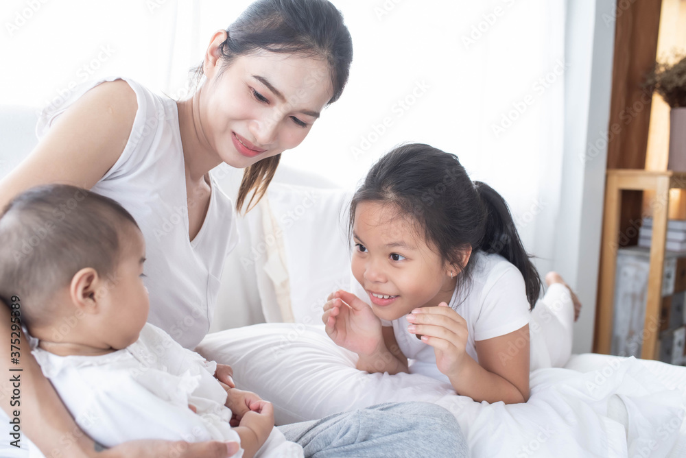 happy loving family. Love, trust and tenderness concept. Mother and child on a white bed. Parent and little kid relaxing at home. Mother and her daughters children girls playing and hugging. happy loving family. Love, trust and tenderness concept. Mother and child on a white bed. Parent and little kid relaxing at home. Mother and her daughters children girls playing and hugging.