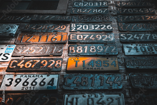 Collage of old, rusty and grungy car license plates over a brick wall illuminated by sun rays