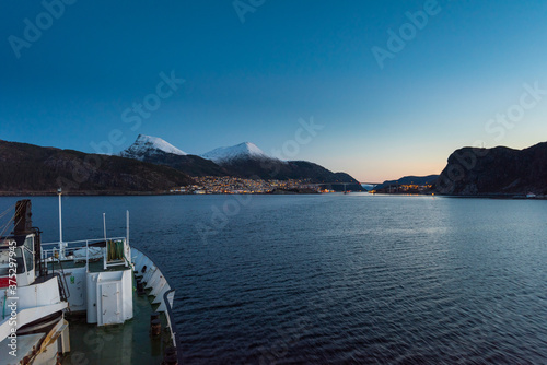 Arriving in Maloy, Norway with cruise ship in early morning with snow capped mountains on clear winter day