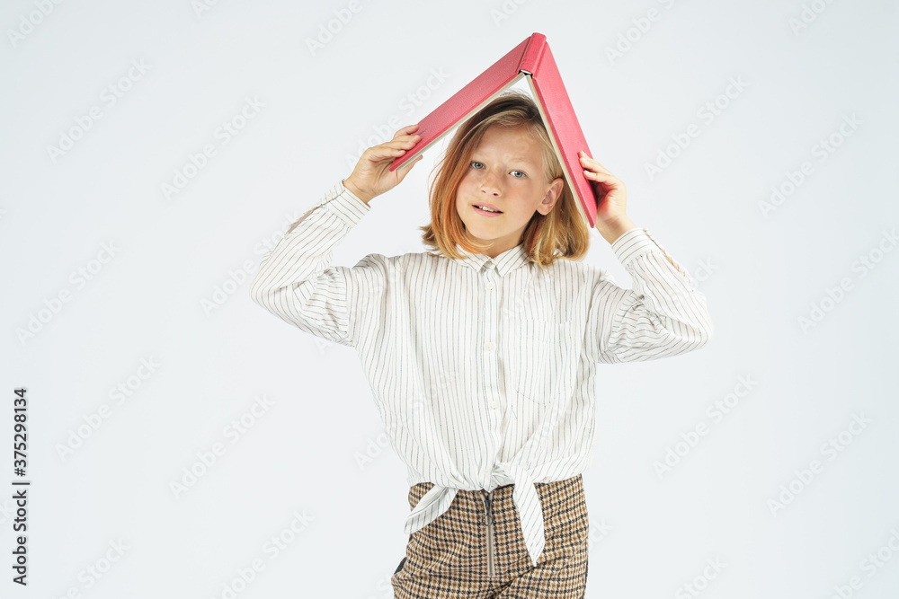 Teenager girl holding an open book above her head. Isolated background. Teenager girl holding an open book above her head. Isolated background.