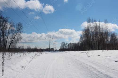 road through the forest with electric towers wires for driving cars in winter