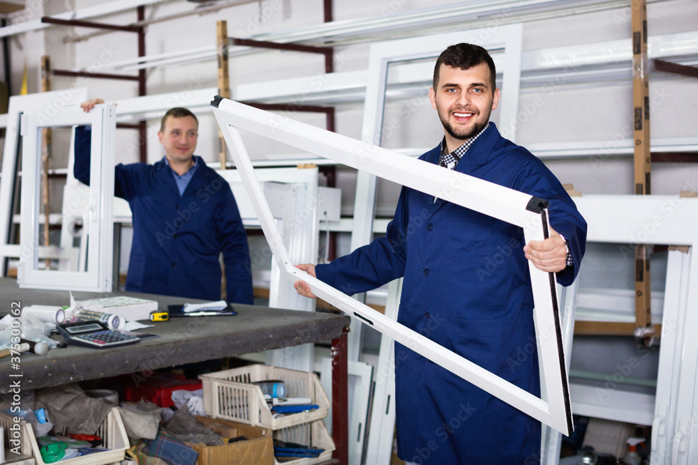 Two cheerful careful workmen inspecting PVC manufacturing output in workshop