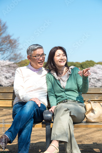ベンチに座り花見をするミドル夫婦 © Paylessimages