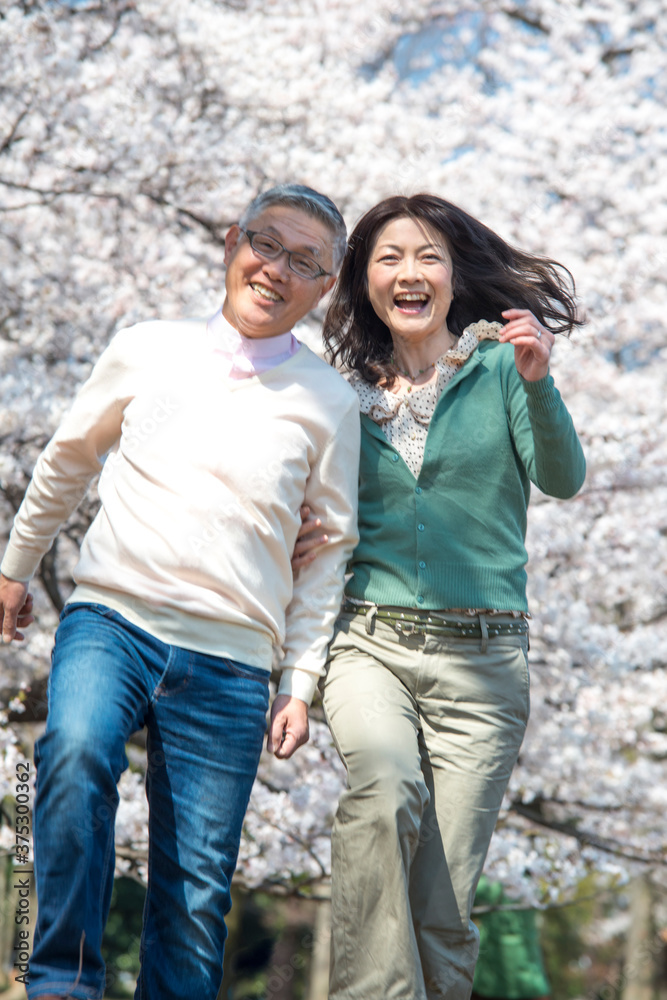 Photography 桜の下でスキップをするシニアカップル
