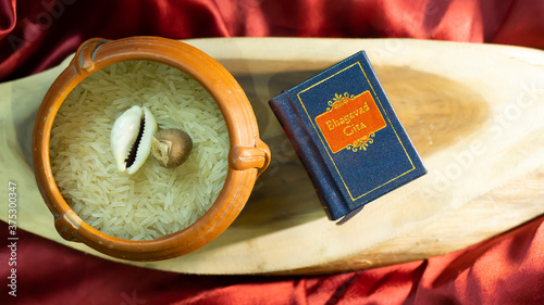 Hindu holy book and cowrie shell on a wooden surface with golden satin cloth 