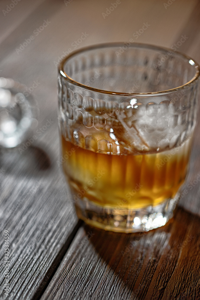 Whisky, bourbon or cognac in glass with ice ball and crystal bung on wooden table. Alcohol drink background Whisky, bourbon or cognac in glass with ice ball and crystal bung on wooden table. Alcohol drink background