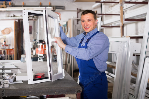 Guy worker is demonstrating the window frame in workshop.