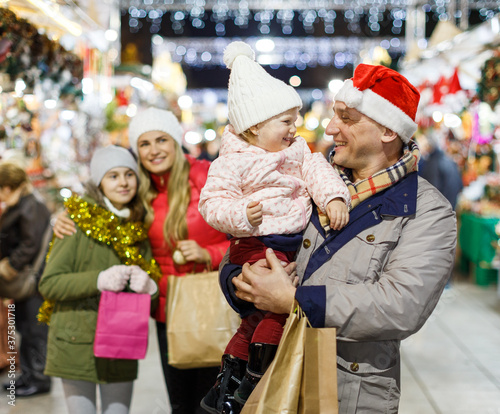 Family portrait of smiling parents with their two nice daughters at Christmas fair