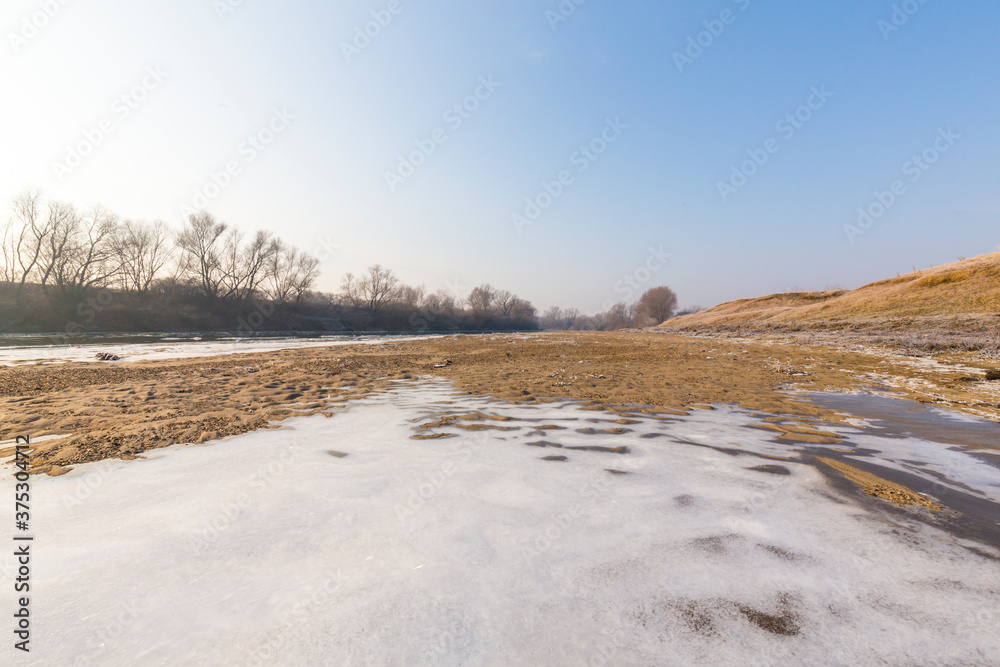 Cold winter morning on a wild river bank, with frost and fresh snow