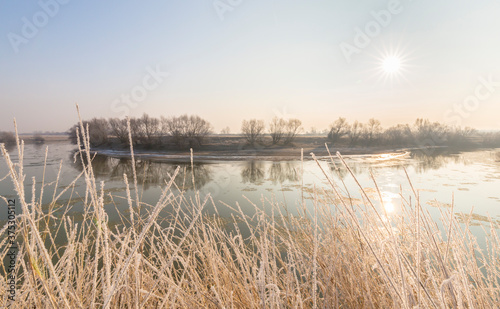 Cold winter morning on a wild river bank, with frost and fresh snow