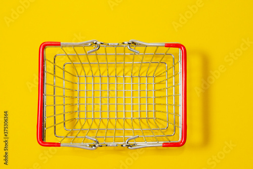 Top view of supermarket shopping basket on a yellow background. Black Friday sale concept.