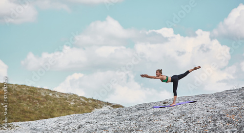 Woman balancing on leg. Female training flexibility outdoors. Yoga or Contemplation idea. Sporty lifestyle on Nature. © oleg_chumakov