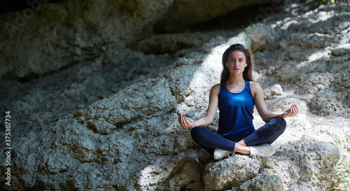 Female in lotus position. Outdoors training. Meditation or Yoga time and Pilates idea. Nature and Magnificent stones.