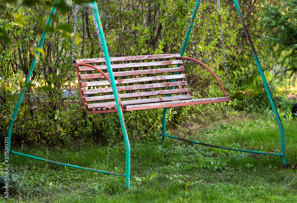 Garden old wooden swing in the backyard of a rural house. Garden old wooden swing in the backyard of a rural house.