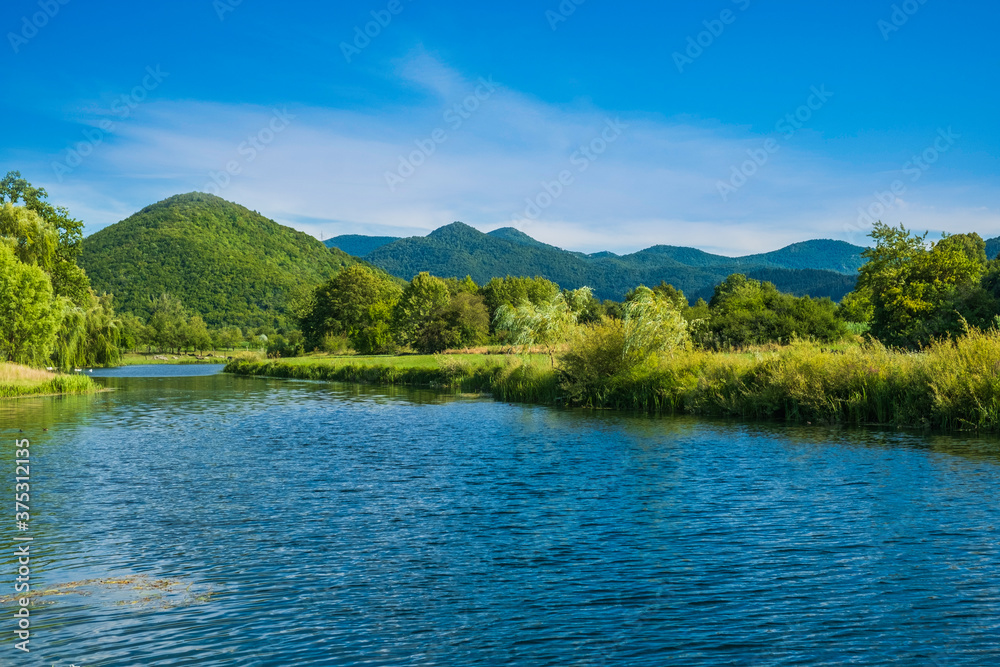 Croatia, beautiful river Gacka flowing between the green meadow fields in Lika region Croatia, beautiful river Gacka flowing between the green meadow fields in Lika region