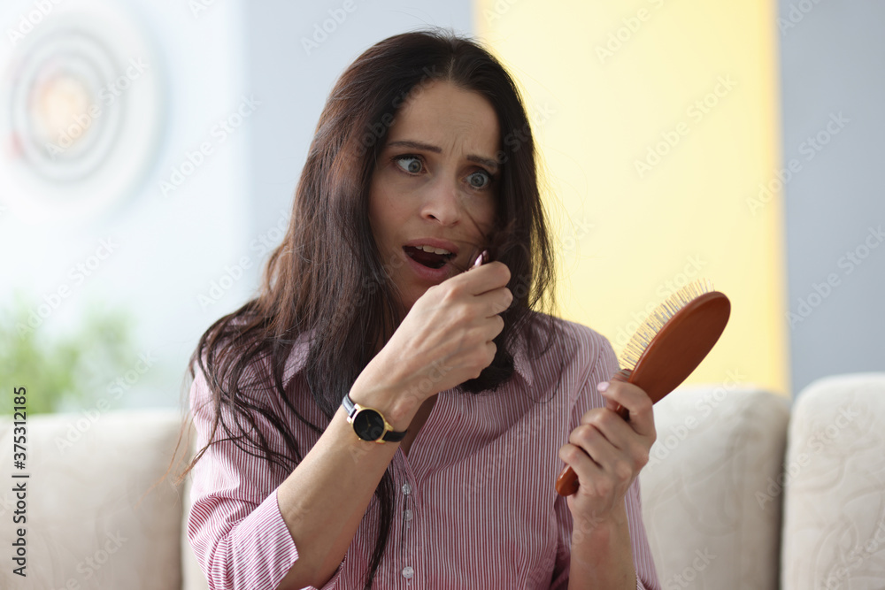 Frightened woman holds comb in her hands and looks at her hair. Split ends hair treatment concept Frightened woman holds comb in her hands and looks at her hair. Split ends hair treatment concept