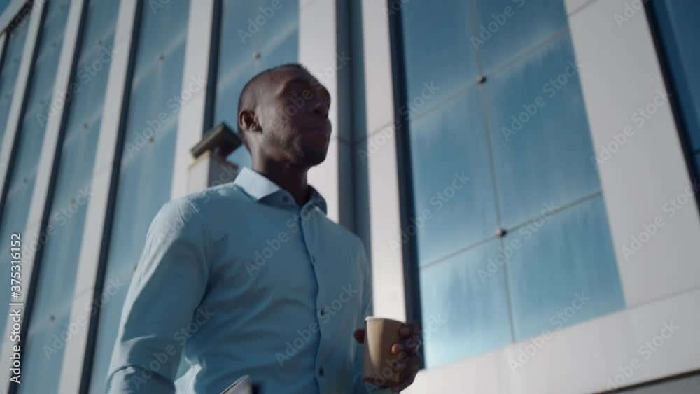Successful African American business man walks down the street near a business office Successful African American business man walks down the street near a business office