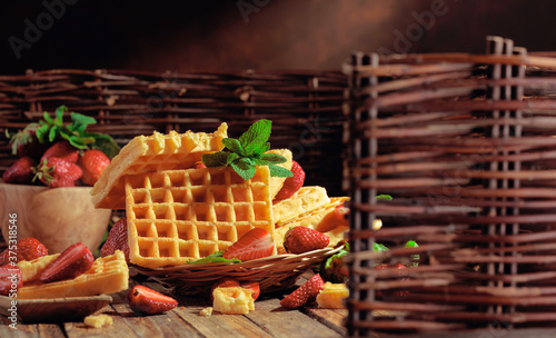 Waffles with strawberries and mint twig.