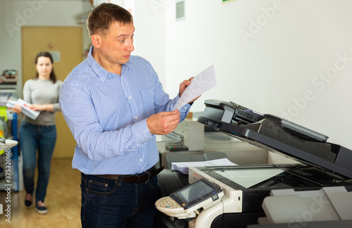 Confident businessman using printer in office. High quality photo