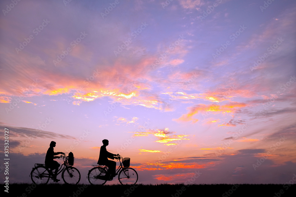 Fototapeta premium 夕陽を背景に自転車通学する男女のシルエット