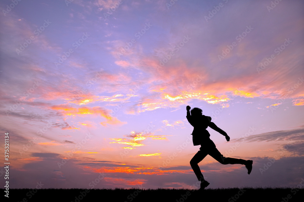 夕陽を背景に元気よく走る男性のシルエット