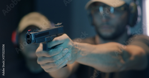 Middle aged shooter firing pistol photo