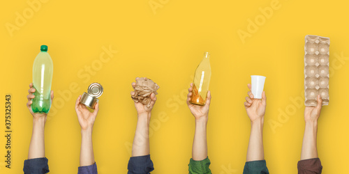 Hands hold trash on a yellow background.