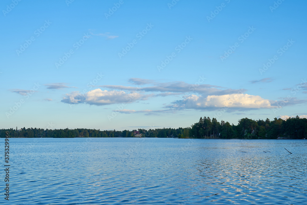 Sunset over the lake with reflection of clouds in water and forest on the horizon. Copy space.