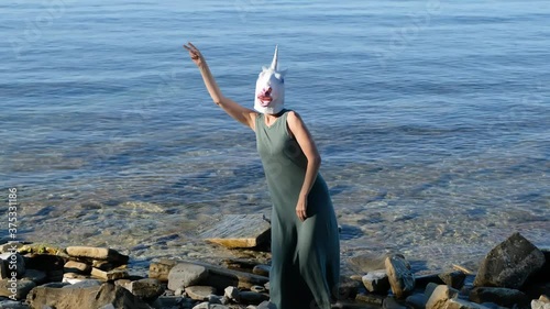 Woman with unicorn head mask dancing in the sea, strange funny weird video.