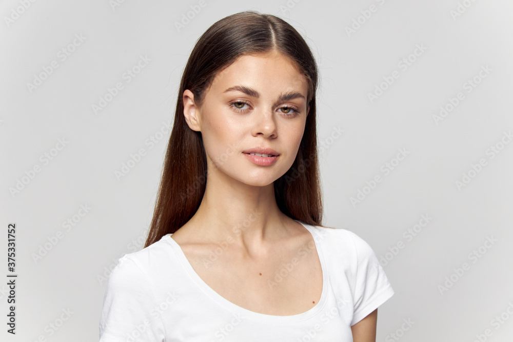 Beautiful brunette girl in a white t-shirt looks ahead on an isolated background close-up Beautiful brunette girl in a white t-shirt looks ahead on an isolated background close-up