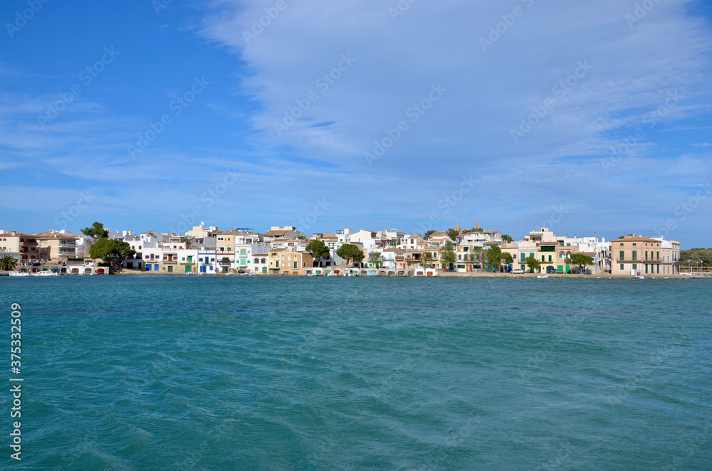 Port of the coastal town Portocolom on Balearic island Mallorca, Spain, panoramic view, colorful traditional houses in the background, turquoise mediterranean sea in front, a sunny day, copy space