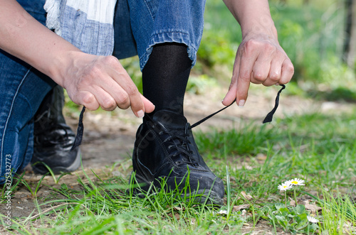 Woman Tying Shoelaces on a Path with Grass.