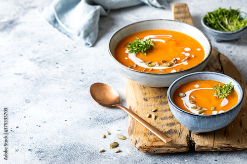Vegetarian autumn pumpkin and carrot soup with cream, seeds and cilantro micro greens. Comfort food, fall and winter healthy slow food concept