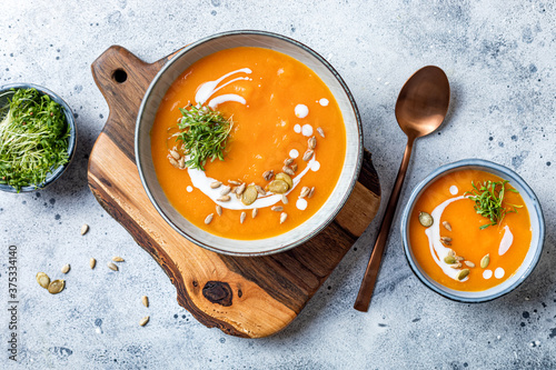 Vegetarian autumn pumpkin and carrot soup with cream, seeds and cilantro micro greens. Comfort food, fall and winter healthy slow food concept photo