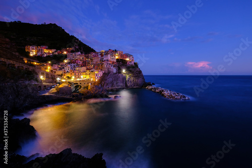 Colorful traditional houses on the rock over Mediterranean sea on dramatic sunset, Manarola, Cinque Terre, Italy