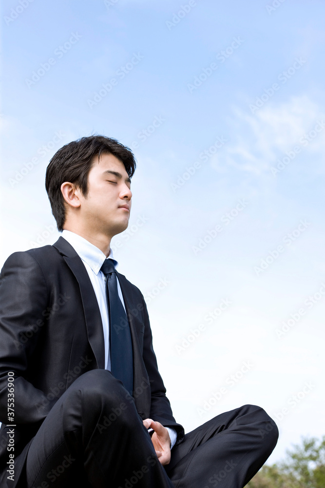 young businessman meditating in lotus position young businessman meditating in lotus position