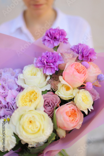 Colorful flowers assorted bouquet in color paper. Holiday celebration concept. Bouquet of beautiful flowers in hands. Colorful flowers bouquet wrapped in paper