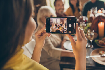 Photo of full family gathering small daughter hold telephone shoot portrait season traditional event friendship dinner big table turkey generation in home evening living room indoors
