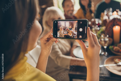Photo of full family gathering small daughter hold telephone shoot portrait season traditional event friendship dinner big table turkey generation in home evening living room indoors