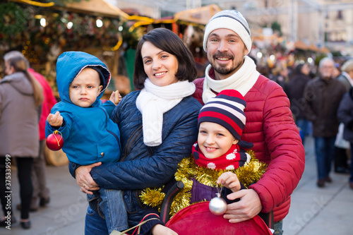 Family of four choose holidays decorations at Christmas market