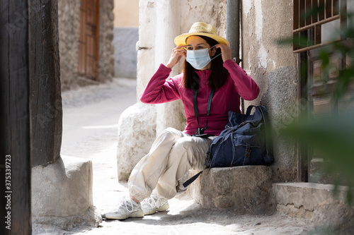Woman resting from her walk with mask and hat