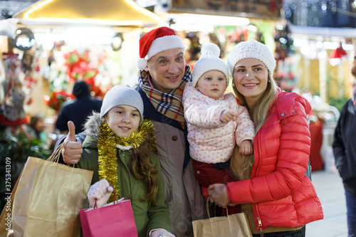 Family portrait of smiling parents with their two nice daughters at Christmas fair