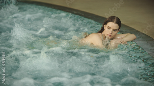 Closeup young woman relaxing in whirlpool bath. Beautiful girl enjoying jacuzz