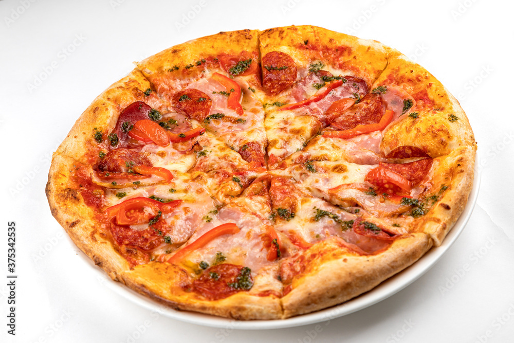 pizza with ham, sausage and tomatoes on a white plate