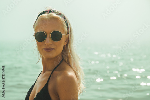 An attractive happy blonde women looking at camera with a smile on a beach with foggy sea in background
